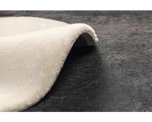 Detailansicht eines runden, hellen Teppichs mit hochflorigem Flor