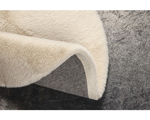 Detailansicht eines beigen Teppichs mit hohem Flor und Textilrücken