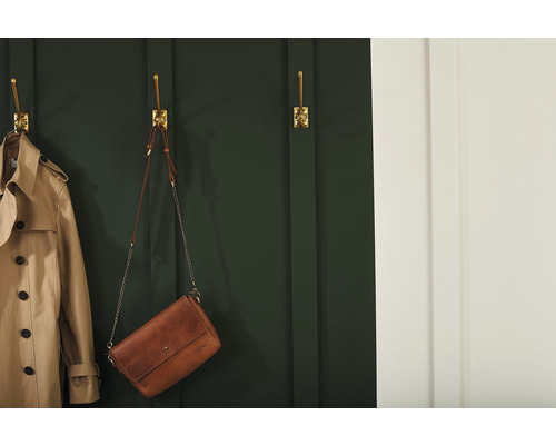Scène avec un trench-coat et un sac à main suspendus à des crochets muraux dorés