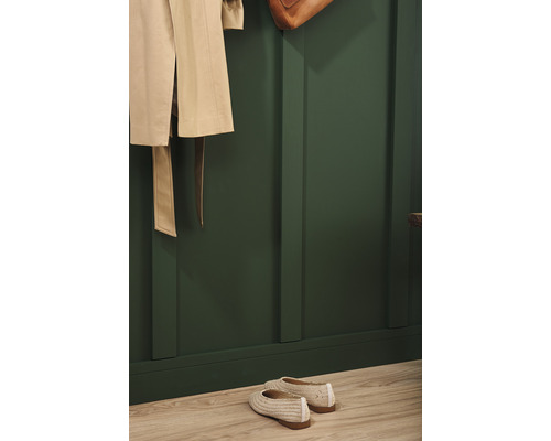 Garderobe mit beige Mantel, Tasche und Schuhen vor einer grünen Wand mit Holzpaneelen
