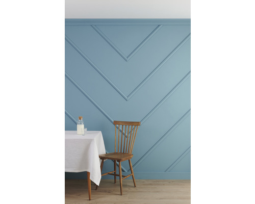 Cuisine lumineuse avec mur lambrissé bleu, table et chaise en bois.