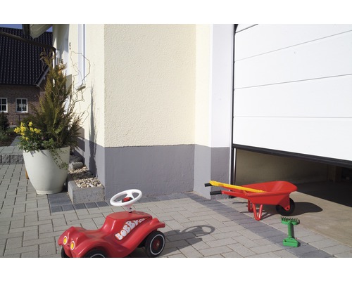 Aussenansicht eines Hauses mit einem Bobby Car und einer Schubkarre vor einer Garage