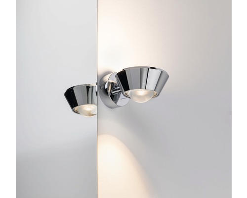 Verchromte Wandleuchte mit Leuchtmittel an weisser Wand