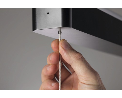 Hand justiert Kabellänge an einer Deckenleuchte