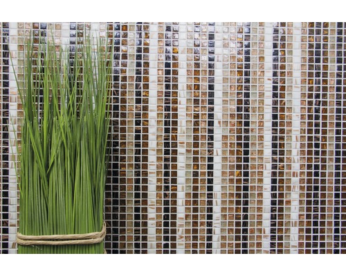Plante artificielle verte décorative devant un mur de mosaïque en verre