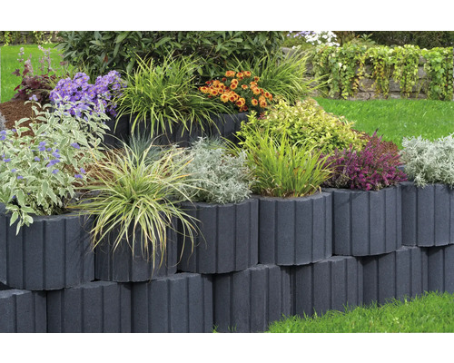 Gestapelte Pflanzsteine mit verschiedenen Pflanzen in einem Garten.