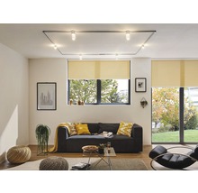 Wohnzimmer mit grauer Couch, Rollos an den Fenstern und Deckenleuchte mit Strahlern.