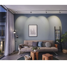 Salon avec canapé, tables d''appoint en bois, lampadaire et système de rails avec spots au plafond
