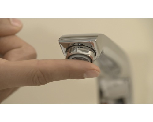 Gros plan d''une main touchant un aérateur de robinet