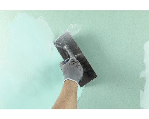 Artisan utilisant une spatule pour appliquer du mastic sur un mur