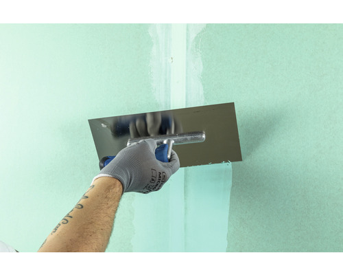 Une personne lisse un mur avec une lisseuse.