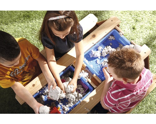 Kinder spielen mit einer Matschküche im Freien mit Sand und Behältern.