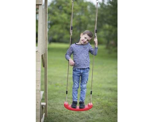 Garçon debout sur une balançoire pour enfants avec des cordes dans le jardin.