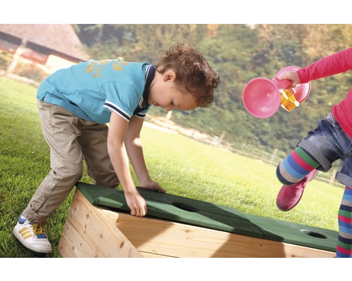 Des enfants jouent avec un bac à sable dans le jardin.