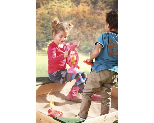 Des enfants jouent avec des jouets de sable dans un bac à sable.
