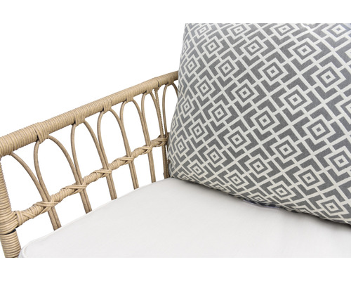 Gros plan d''un fauteuil en rotin avec coussin et motif géométrique