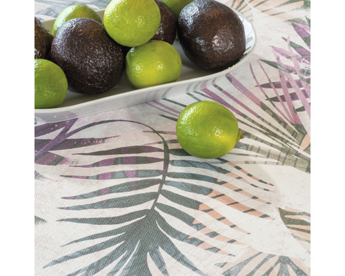 Avocats et citrons verts sur une assiette sur une nappe à motif de feuilles.