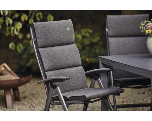 Chaise de jardin rembourrée en métal avec accoudoirs devant un jardin en arrière-plan