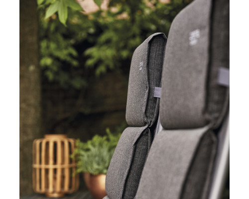 Gros plan de coussins de meubles de jardin gris avec des plantes en arrière-plan