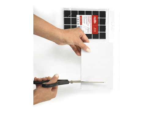 Eine Person schneidet einen Filzgleiter mit einer Schere zu. Filzgleiter zum Zuschneiden sind im Hintergrund zu sehen.