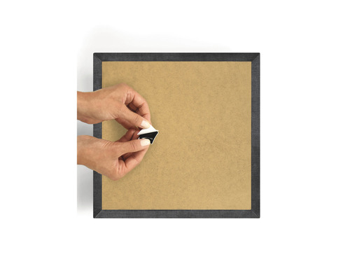 Person befestigt eine selbstklebende Aufhängung an einer Bilderrahmenrückwand.