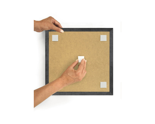 Person befestigt Klebepads an einem Bilderrahmen
