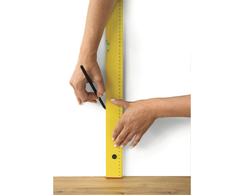 Person zeichnet eine Linie mit Bleistift und Wasserwaage an einer Wand.