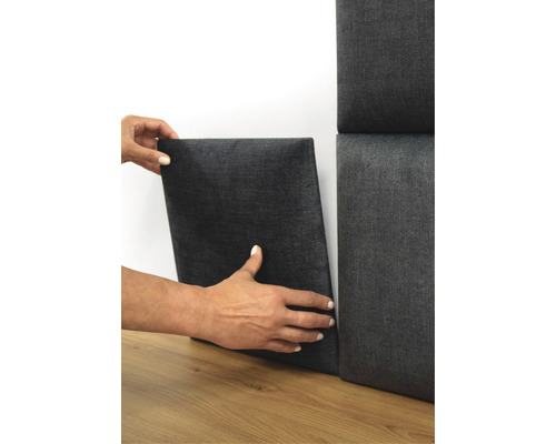 Person befestigt Akustikpaneel an der Wand