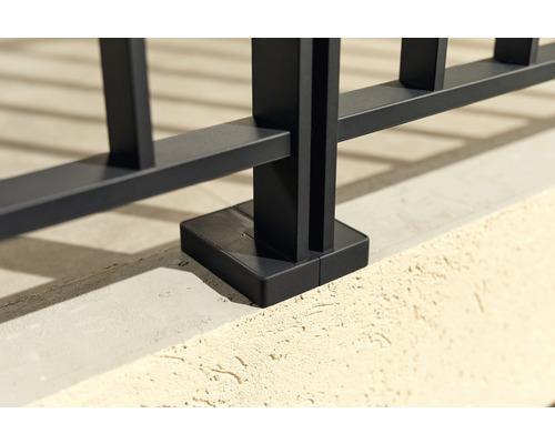 Detailaufnahme eines schwarzen Metallzauns mit Bodenbefestigung.