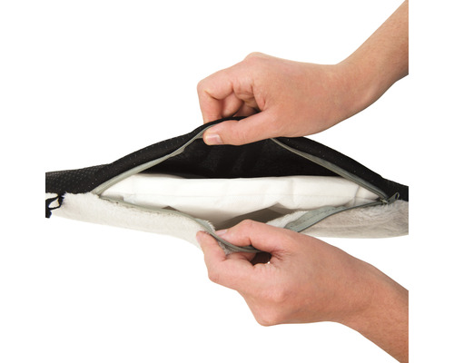 Des mains ouvrent la fermeture éclair d''un lit pour chien.