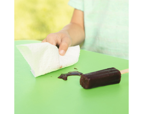 Un enfant essuie la glace fondue avec un essuie-tout sur une table