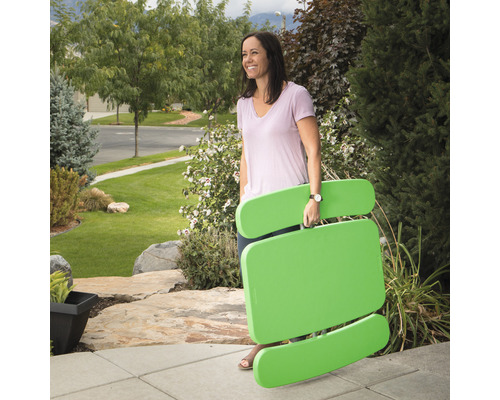 Femme portant une table de pique-nique pliée à l''extérieur.