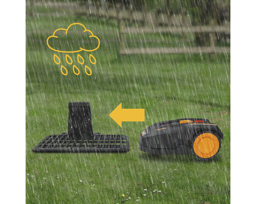 Un robot de tonte rentre à sa station de charge sous la pluie.