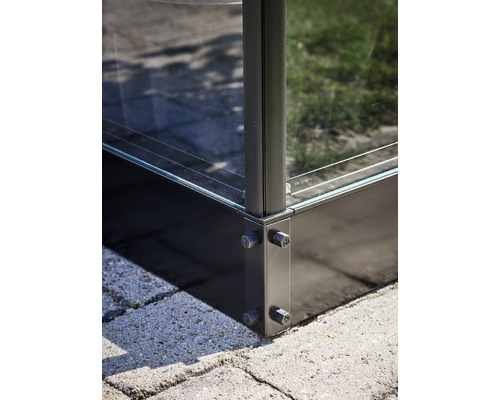 Detailaufnahme eines Glaszauns mit Metalleckverbindungen auf Pflastersteinen