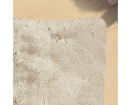 Vue détaillée d''un tapis à poils longs beige rectangulaire.