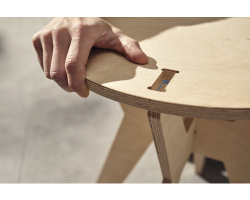 Une personne tient un tabouret en bois contreplaqué.