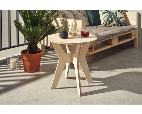 Table d''appoint en bois avec boisson, petit pot et collations sur un balcon avec plante et canapé en palettes