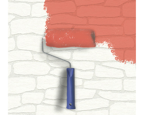 Rouleau à peinture avec de la peinture sur un mur en pierre