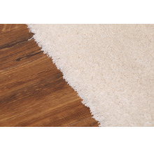 Detailansicht eines hellen Teppichs auf Holzboden