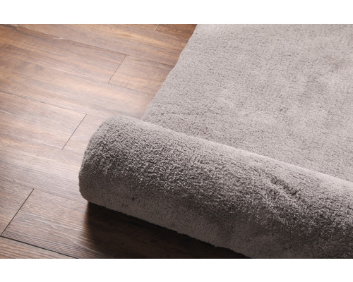 Tapis en tissu, partiellement enroulé, sur plancher en bois