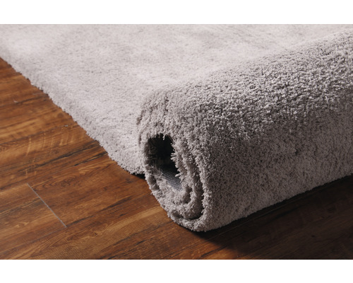 Tapis gris sur plancher en bois, partiellement enroulé