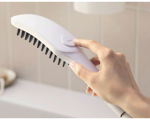 Eine Hand bedient eine weisse Bürste mit schwarzen Borsten.