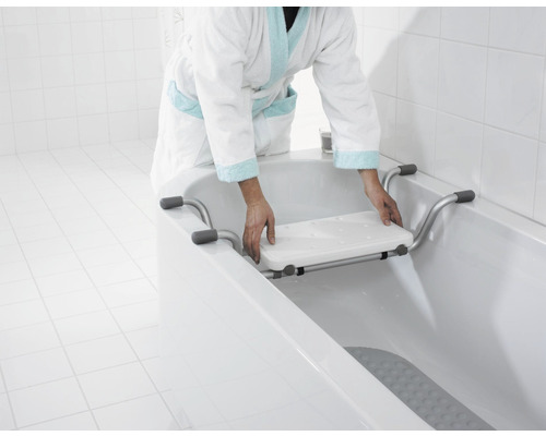 Une personne installe une planche de baignoire dans une baignoire