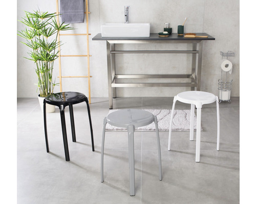 Badezimmer-Szene mit drei Hockern in Schwarz, Grau und Weiss vor einem Waschbecken.