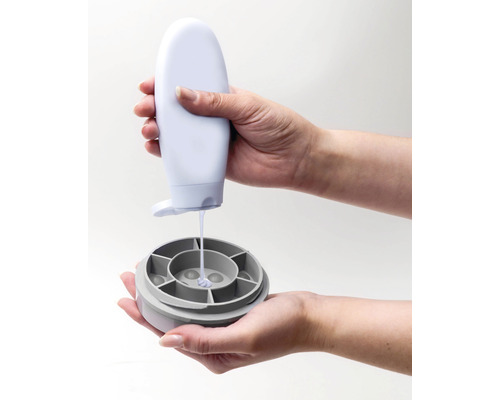 Une personne verse du liquide d''une bouteille dans un récipient.