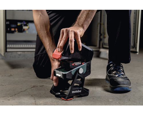 Une personne insère une batterie dans une lampe de chantier sans fil Metabo.