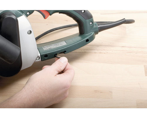 Raboteuse avec logo Metabo et main sur table en bois