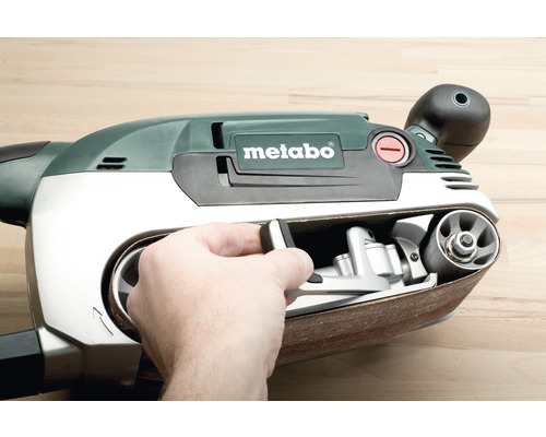 Ponceuse à bande avec une main sur la commande et le logo Metabo