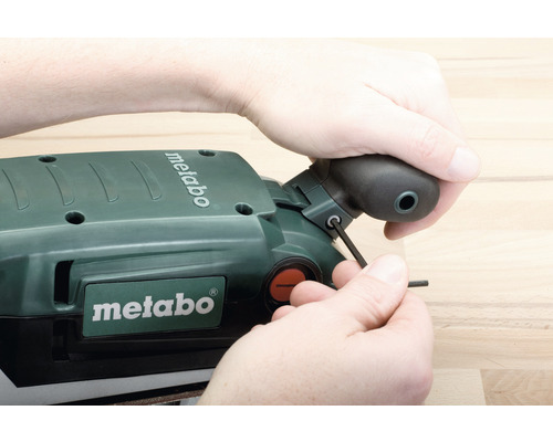 Personne réglant une ponceuse Metabo avec une clé Allen. Logo Metabo visible.