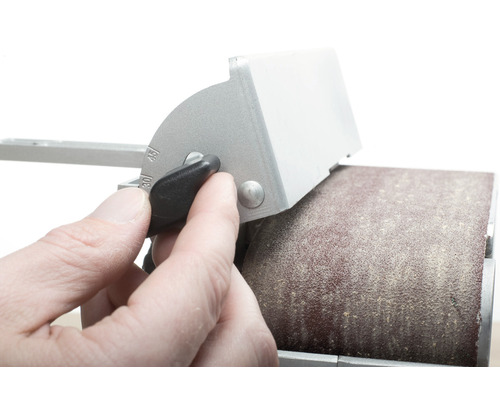 Une personne ajuste le guide d''angle d''une ponceuse à bande.